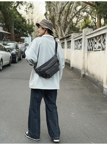 Charcoal grey tactical chest bag with adjustable strap worn in an urban outdoor setting