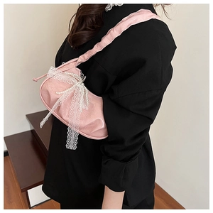 Pink shoulder bag detail with white lace bow and elegant pearl tassels in a soft setting
