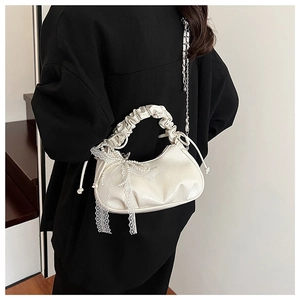 Détail d'un sac demi-lune blanc crème avec des nœuds en perles et bordures en dentelle