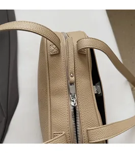 Nahaufnahme des silbernen Reißverschlusses und des Lederkorns der beigen Schultertasche