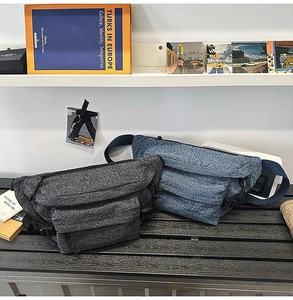 Detail of washed denim sling bag with multiple zipper compartments and adjustable strap