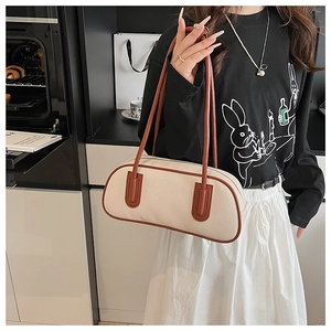 Dettaglio della borsa a tracolla in tela beige e pelle marrone indossata da una modella