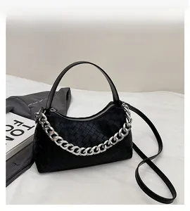 Detailed view of black woven leather handbag with chunky silver chain and strap