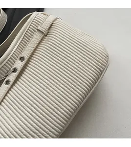 Detailed macro view of the cream pleated leather texture and silver eyelet buckles