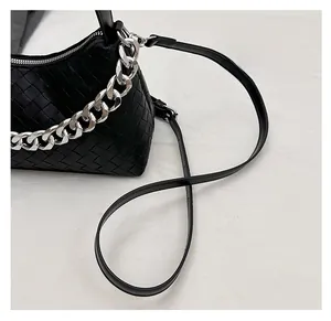 Close-up of black woven leather handbag featuring a bold silver chain and fine strap