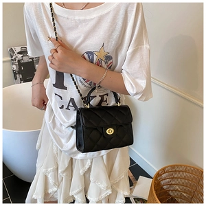 Close-up of black quilted crossbody bag with gold turn-lock clasp and chain strap detail