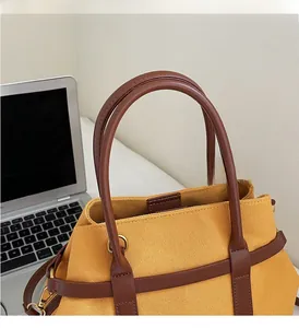 Détail du sac cabas en toile jaune avec anses en cuir marron pour le travail