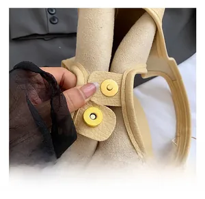 Detail of light gold magnetic clasp on beige textured leather bucket bag with suede lining