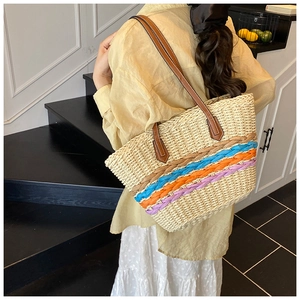 Detailed side view of large woven straw tote bag with colorful wave patterns and leather straps