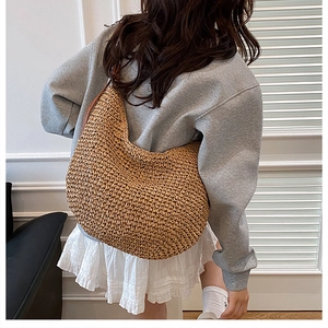 Detail of hand-woven straw shoulder bag showing textured paper rope craftsmanship