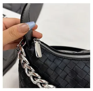 Close-up of black woven leather handbag showing smooth silver metal zipper detail