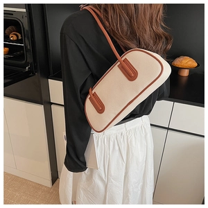 Dettaglio della borsa sottobraccio in tela crema con finiture in pelle marrone ed elegante