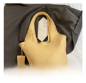 Detail shot of a cream yellow lychee grain leather tote bag on a grey blazer