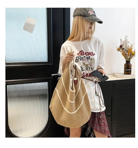 Detail of hand-woven straw tote bag with white U-shape stripes and soft texture