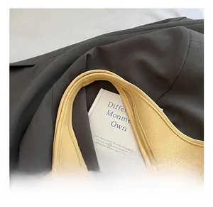 Detailed close-up of wide handles on a light yellow leather bucket bag with pebble texture
