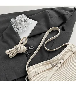 Detail view of cream pleated leather bucket bag with silver metal hooks and long strap