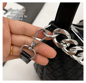 Detail of the detachable shoulder strap with silver lobster clasp on black woven bag