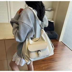 Detail of cream white leather hobo bag featuring a metal buckle and front pocket