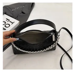 Interior view of black woven shoulder bag with silver chain and white lining compartment