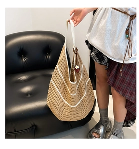 Detailed texture of hand-woven straw tote bag with white stripes and strawberry charm