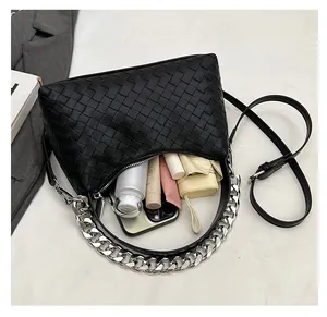 Spacious black woven shoulder bag showing interior capacity with phone and umbrella