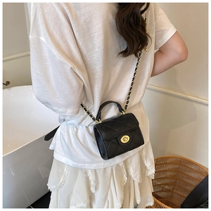 Detail of black quilted leather crossbody bag with gold hardware and chain strap