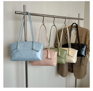 Cinq cabas vintage de différentes couleurs avec nœud suspendus à un support en métal