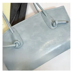 Gros plan d'un cabas en cuir bleu clair avec nœud design et détails de finition en métal