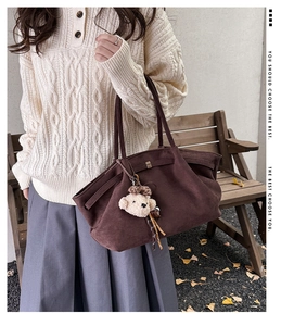 Close-up of coffee brown tote bag with suede texture and a cute plush bear charm detail