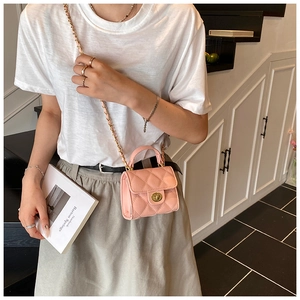 Close-up of pink quilted mini bag with gold chain strap and twist lock detail