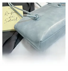 Détail du sac cabas en cuir bleu avec poignée nouée et détails en métal argenté