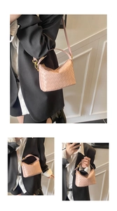 Detail of light pink woven crescent bag with gold hardware shown on a female model