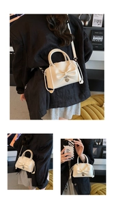Tre viste di una borsa a secchiello beige con fiocco e ciondolo a cuore su blazer nero