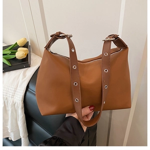 Détail de la bandoulière réglable avec œillets métalliques argentés sur un sac en cuir
