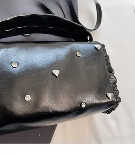 Close-up of black rivet bag featuring heart-shaped studs and soft pleated texture