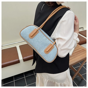Detail of light blue denim fabric texture and brown leather trim on shoulder bag