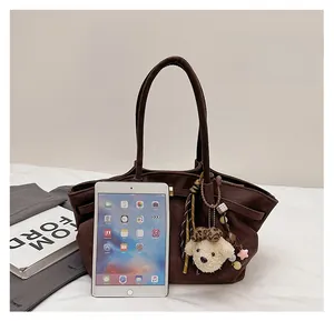 Macro view of dark brown suede bucket bag texture and charms with tablet for scale