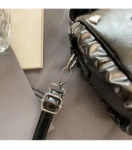 Detail of glossy black leather bag featuring silver heart studs and ruffled edge design