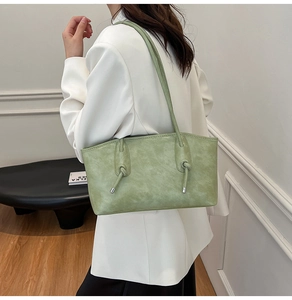 Détail du cabas vert sauge avec nœud à pompon et texture en cuir mat sur une épaule