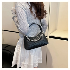 Close-up of black woven leather handbag showing silver chain and Intrecciato craft