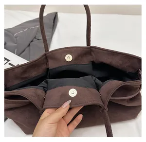 Detail shot of the secure gold magnetic snap closure on a dark brown suede tote bag
