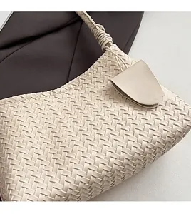 Close-up of cream woven leather texture and detailed handle on a stylish handbag