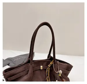 Detail view of durable brown suede tote handle with metal buckle and beaded charm
