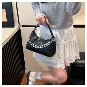 Detail view of woven black leather texture and chunky silver chain on hobo shoulder bag