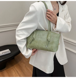 Détail du sac à bandoulière en cuir vert clair avec nœud décoratif sur la fine lanière