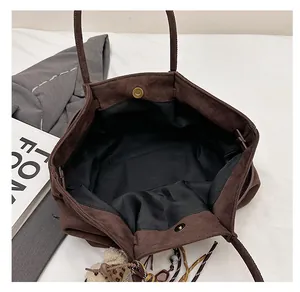 Macro view of brown suede tote bag interior featuring large capacity and magnetic buckle
