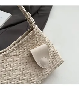 Close-up of beige woven shoulder bag featuring intricate knot details and hanging tag