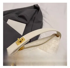 Detail showing cream woven texture and golden twist lock on a luxury handbag