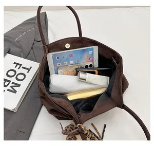 Detail of spacious dark brown suede tote bag interior with magnetic closure and charm