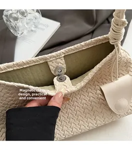 Detail of woven cream handbag featuring a magnetic clasp and olive green suede lining